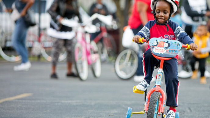 A young boy in a helmet tests out a new bicycle