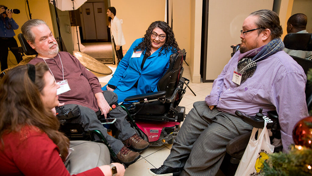 Four people using wheelchairs sit together in a circle