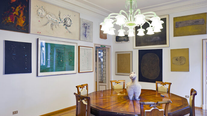 A dining room with an ornate wooden table and several paintings on the walls.