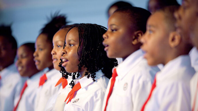 A row of young singers in white shirts and red ties.