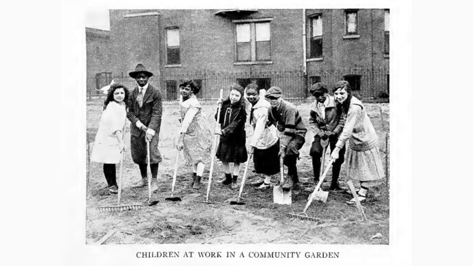Old black-and-white photo of a town of children holding garden tools.