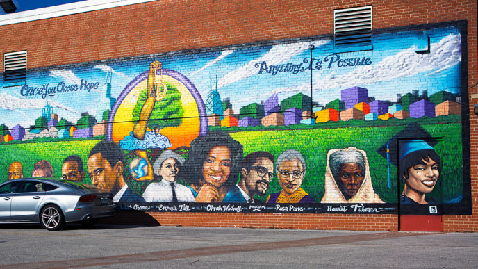 A mural on a brick wall shows historic figures in front of Chicago’s skyline with the words Once You CHoose Hope Anything Is Possible
