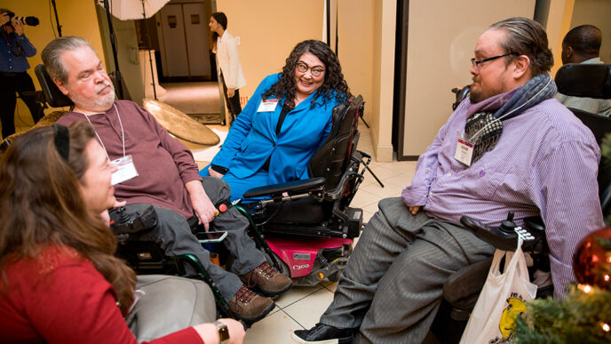 Four people using wheelchairs sit together in a circle.