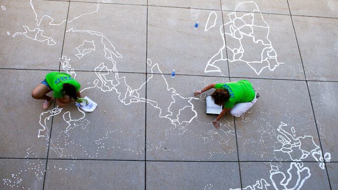 Volunteers painting a map of the world|Volunteers work together on painted artworks for a school|Volunteer Charles climbs a ladder to paint a classroom wall|Volunteer team leader Erin supervises a construction project|Volunteers piece together a mural of the Hammond Elementary mascot.