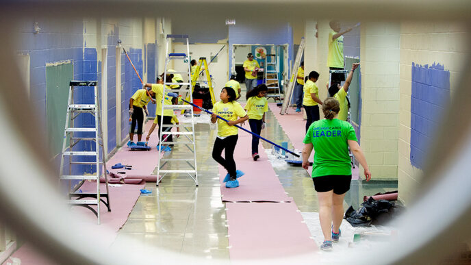 A glimpse through a window at volunteers painting Brighton Park Elementary.