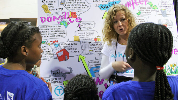 An illustrator from Ink Factory talks to three girls attending We Day.