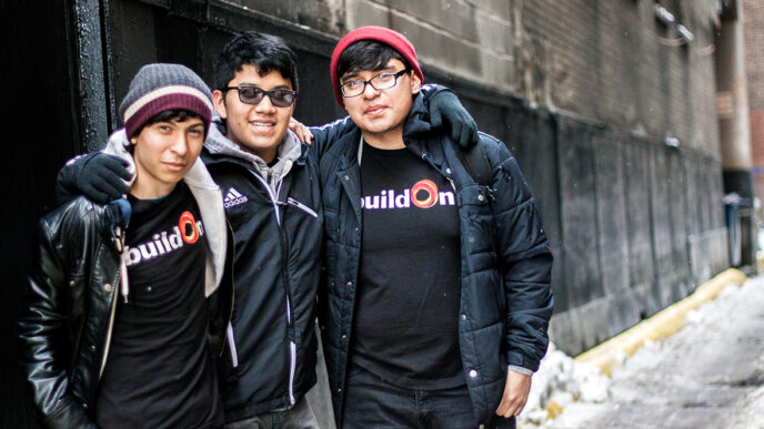 Carlos Leon with two fellow students from the BuildOn program|Lunch bags and handmade greeting cards prepared by students|Three students hand-stitch fleece fabric into warm winter hats.