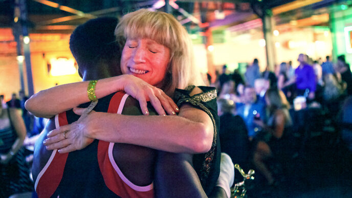 Sally Hazelgrove hugs a young boxer holding a gold trophy|||||||.
