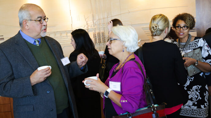 Guests in conversation at the Nuestro Futuro reception|Guests listening and smiling|Panelists seated on the stage|.