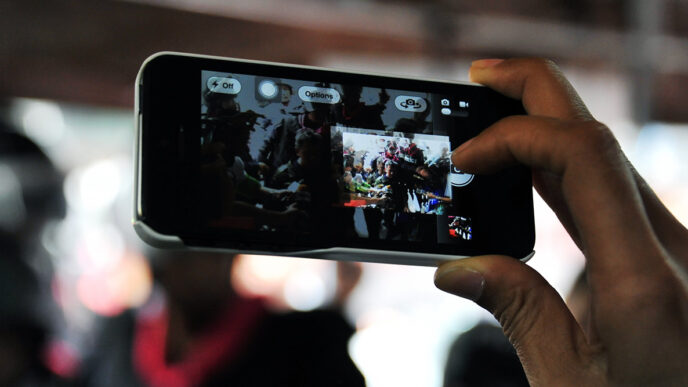 Close-up of a phone taking photos of a group of people.