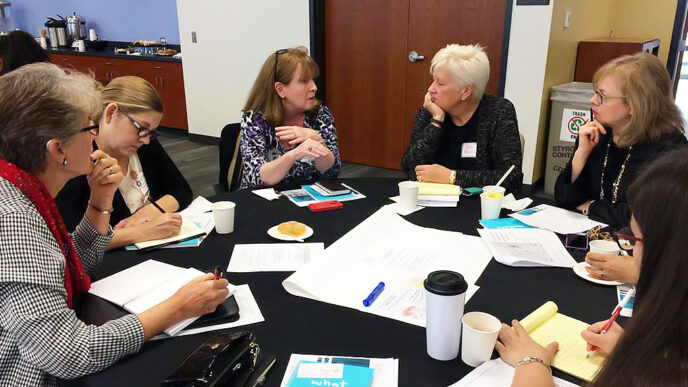 A small group in conversation during an information session hosted by The Lake County Community Foundation|Bar chart contrasting the age distribution of Lake County's population in 1990 and 2025. Young and middle-aged adult populations are declining.