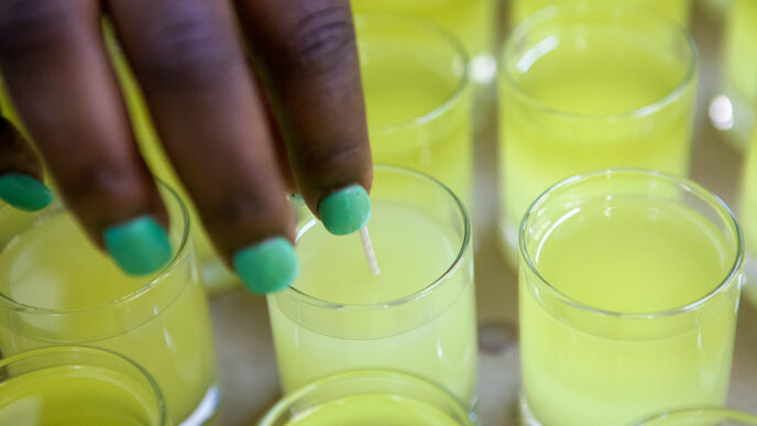 Trainees at Bright Endeavors place wicks into soy votive candles|A training session at the Bright Endeavors workspace|Measuring wax and additives.