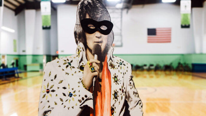 A cardboard cut-out of Elvis Presley in the Lambs Farm gymnasium|A portrait of the Lambs Farm Elvis Club members|Jeanne Curtin shares Halloween stickers with an Elvis Club member|.