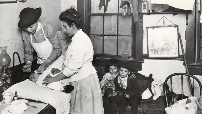 Archival photo of a visiting nurse from Hull House administering eye drops to a baby while its mother and two siblings look on.