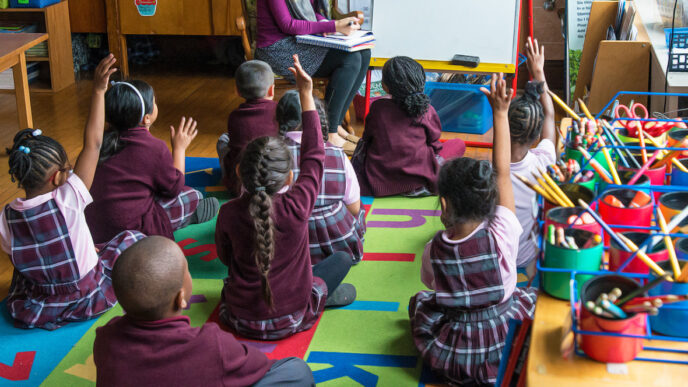 Children sitting on the floor in a first-grade classroom raise their hands|Jenny Fortner and companions at a gala supporting Special Olympics Illinois.