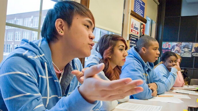 Four high school students in conversation during class|Pie chart representing Chicago high school students served by categories of school. Neighborhood Public High Schools: 42.5%.