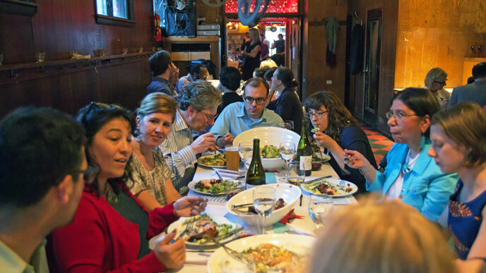 Guests enjoying dinner and talking at an On the Table event at the Hideout.