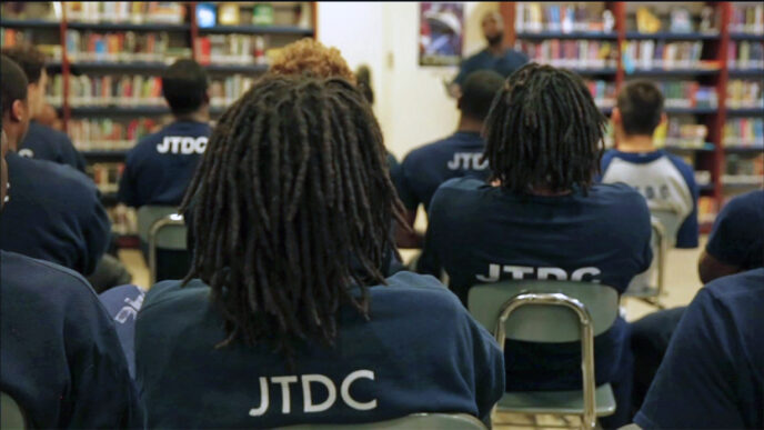 Students in the Cook County Juvenile Temporary Detention Center library|Three young residents in the Juvenile Temporary Detention Center wearing JTDC t-shirts|.