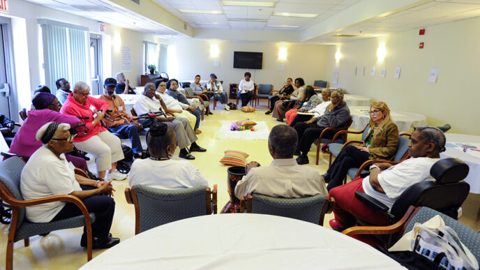 A group gathered in discussion at the Kingston Place senior residence|Laura Morgan addresses the group at her On the Table lunch.