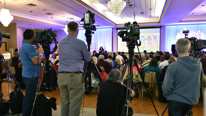 News cameras record the launch event for the Generation All Action Plan|Students from the Kelly High School mentoring program in conversation with event guests|||.