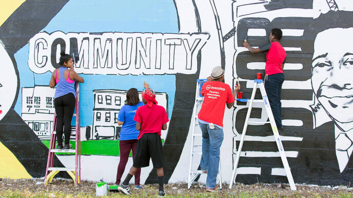 Volunteers create a mural illustrating local history in the Greater Grand Crossing neighborhood.