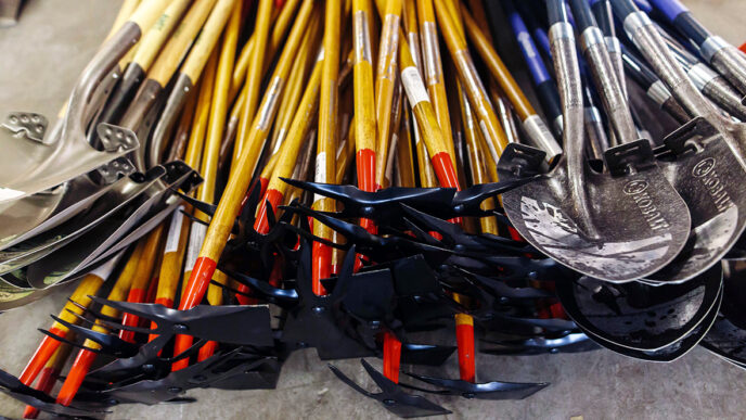 A collection of garden tools|Organizing a collection of garden hoes at the Chicago ToolBank|A volunteer holding a paintbrush|Susan McDonald at the ToolBank warehouse|Two children painting wooden handles for shovels.