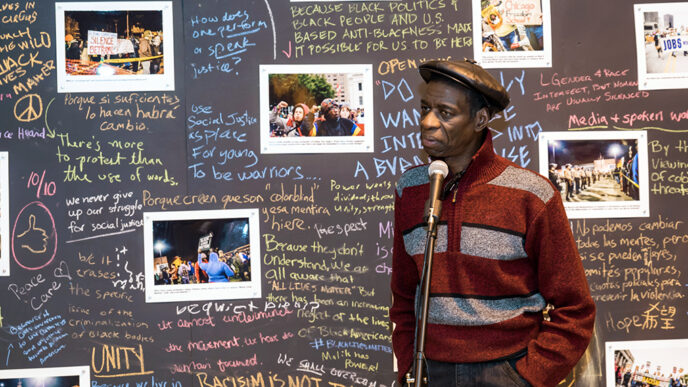 Darrell Cannon in front of photos and handwritten statements about police brutality.