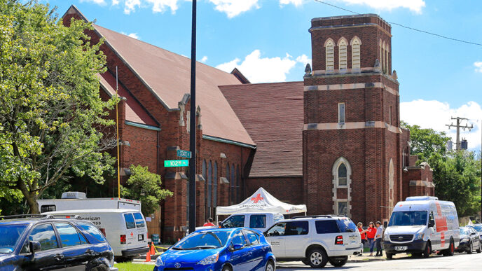 A church in Chicago's Roseland neighborhood|A man on a ladder installs a smoke alarm on a wall|A volunteer with a clipboard reviews a fire safety checklist|Two volunteers on a doorstep talking with a home owner.