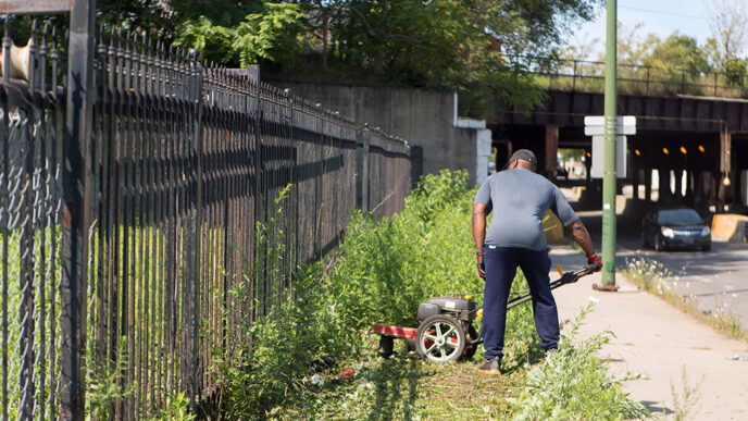 A man mows the grass in a public space in Grand Crossing.