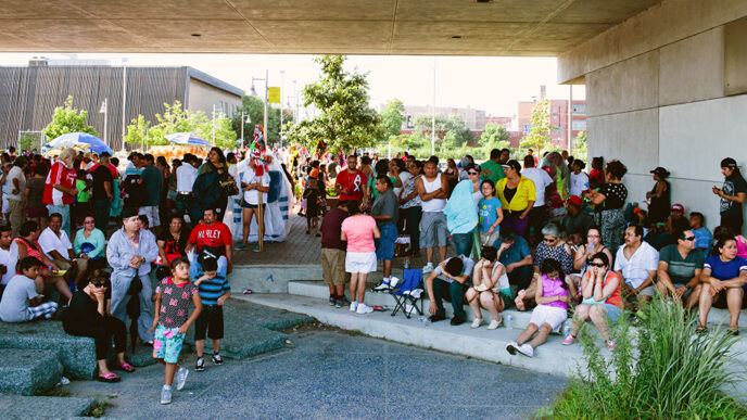 Families gathered in a public square on a sunny day|El Paseo Community Garden.