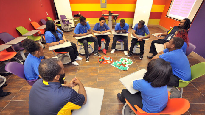 Students sit in a circle in a brightly painted.