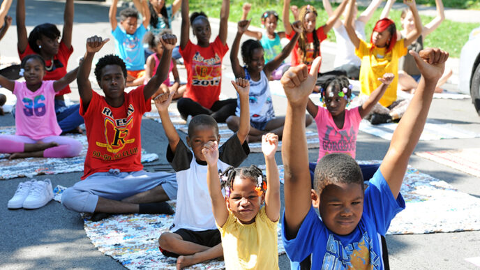 A group of kids sitting cross-legged and stretching.