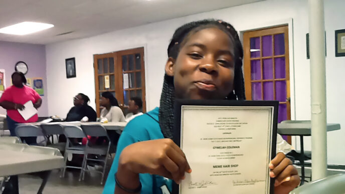 Gymelah Coleman holds a certificate and smiles|||Twenty children smile and pose with their graduation certificates.