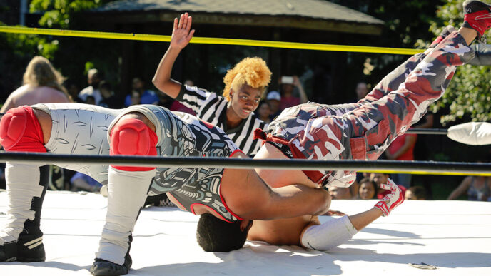 A wrestler attempts to pin an opponent while a referee watches|A wrestler makes an entrance toward the ring.