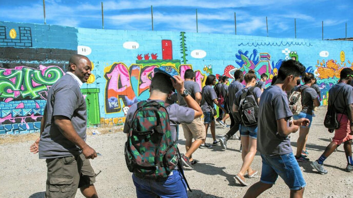 A group of students walking past a brightly colored mural|Chicago Park District Commissioner Jesse Ruiz shakes hands with a young man in the Trust's office boardroom|A group of students on a lawn at the University of Chicago|Matthew Brewer.