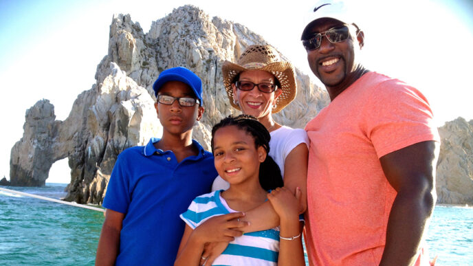 Erika Lyn Huie Downs and family smiling in front of a seaside view.