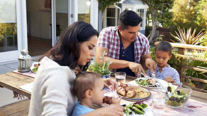 A mother and father sit at an outdoor dining table.