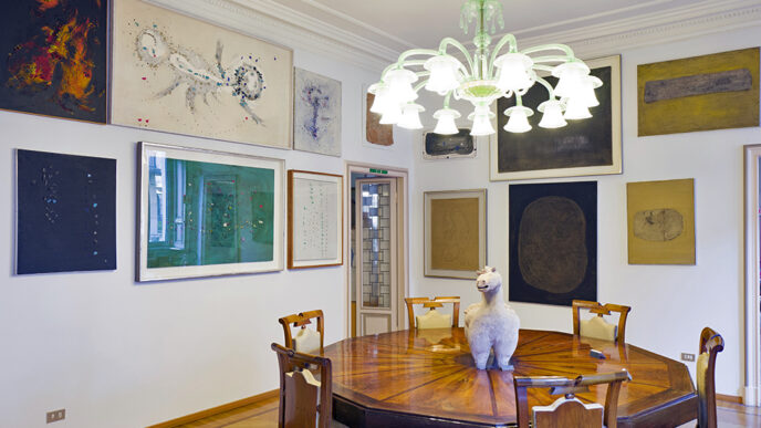 A dining room with an ornate wooden table and several paintings on the walls.