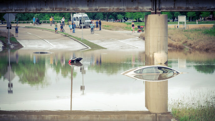 A flooded highway where two cars are partially submerged.