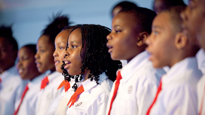 A row of young singers in white shirts and red ties.