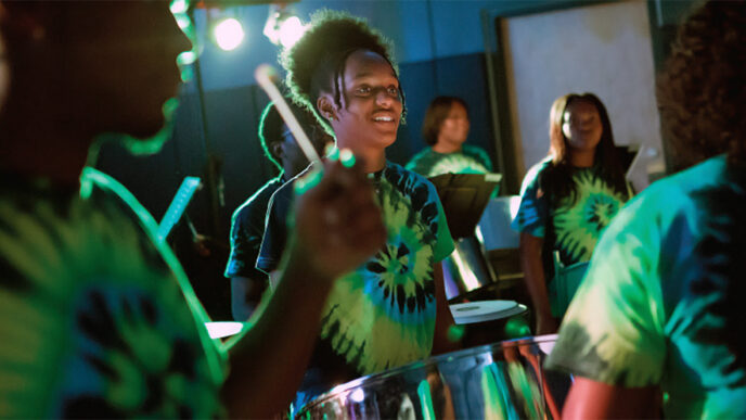 A corps of young drummers in brightly tie-dyed shirts|Map of Chicago neighborhoods showing those served by Springboard grant recipients|Three people in semi-formal wear stand with their arms around each other.