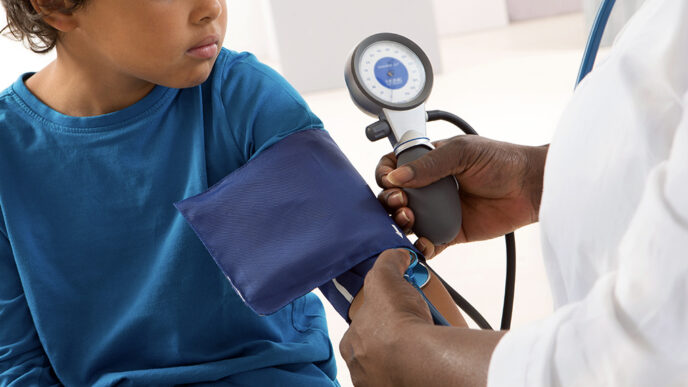 Close-up view of a young child's arm wrapped in a blood pressure cuff.