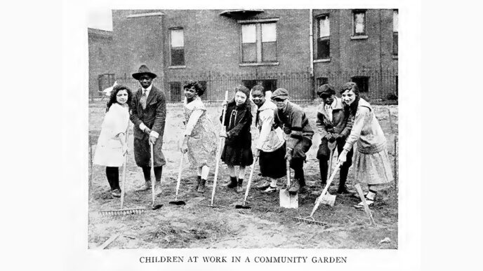 Old black-and-white photo of a town of children holding garden tools.