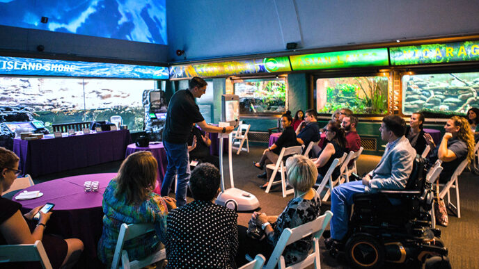 A man demonstrates an electronic device in the center of an aquarium display hall.