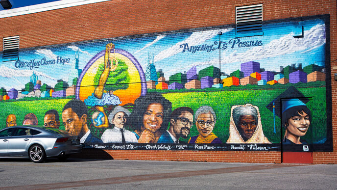 A mural on a brick wall shows historic figures in front of Chicago's skyline with the words Once You CHoose Hope Anything Is Possible.