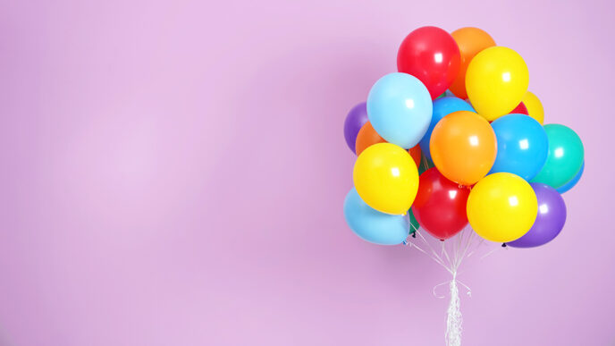 A bunch of colorful balloons against a purple background.