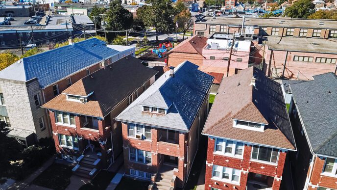 Aerial view of a residential neighborhood with multi-family brick buildings in the foreground and a school with playground behind.