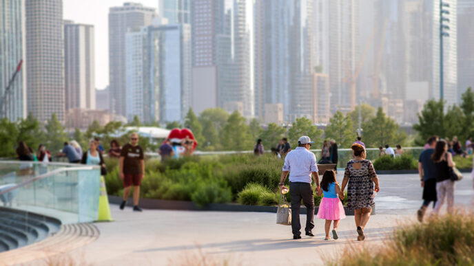 A young girl and her parents walk through a park