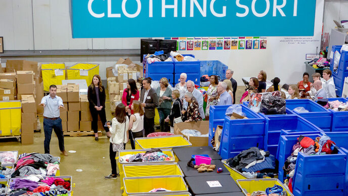 |A woman stands at a podium in front of a sign that says Cradles to Crayons