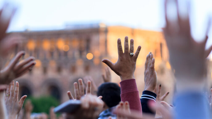 A crowd of people outdoors raising their hands